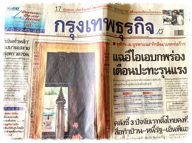 Front page newspaper in Thai language with boy standing in fornt of a pointed tower
